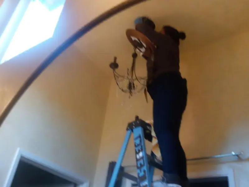 Electrician installing a chandelier in a San Miguel residence